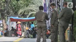 Petugas Satpol PP berjaga saat warga gusuran Kampung Bayam menggelar aksi di depan Balai Kota, Jakarta, Senin (5/12/2022). Nasib warga Kampung Bayam di kawasan Jakarta International Stadium (JIS), Jakarta Utara, kian merana. Meski sudah diresmikan Gubernur DKI Jakarta Anies Baswedan pada 12 Oktober 2022,  sampai saat ini mereka belum bisa menghuni gedung empat lantai tersebut. (merdeka.com/Iqbal S. Nugroho)