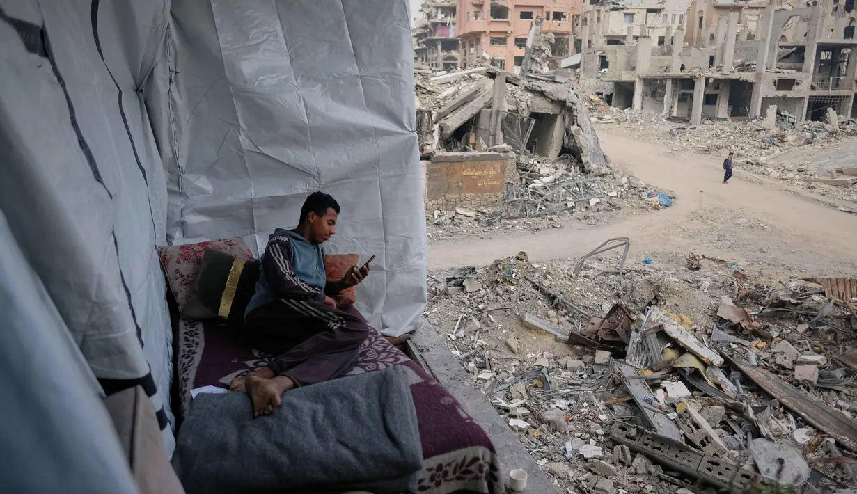 Namun, asa untuk berjuang, bertahan, dan melanjutkan kehidupan terus membara. Tampak dalam foto, Omar Qutay duduk di atas tempat tidur yang diletakkan di balkon rumahnya yang sebagian hancur di lingkungan Al-Karama, Kota Gaza, Rabu, 24 November 2025. (AP Photo/Jehad Alshrafi)