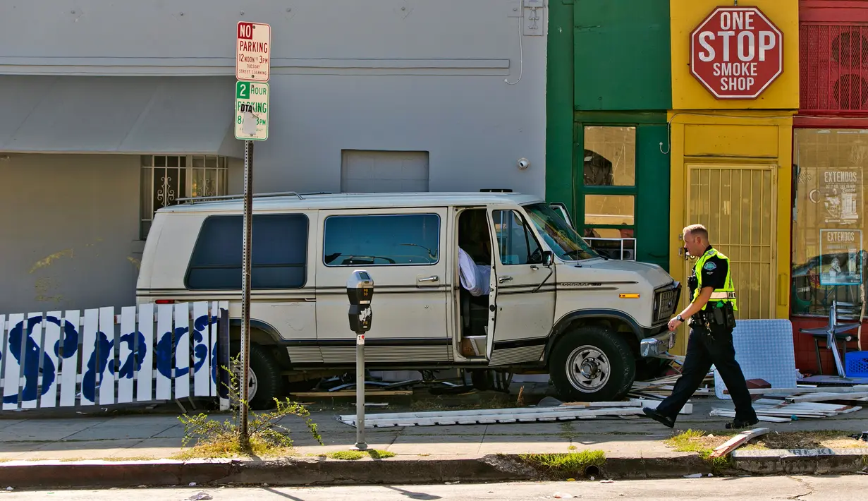 Petugas kepolisian berjalan dekat mobil van yang menabrak kerumunan orang di depan sebuah restoran di Los Angeles, Minggu (30/7). Van itu menabrak truk pickup sebelum menabrak pembatas jalan dan menghantam bagian luar resto. (AP Photo/Damian Dovarganes)