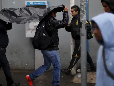 Warga Meksiko melindungi diri dari hujan di luar stasiun bus di Guadalajara, Jumat (23/10). Badai Patricia, salah satu badai terkuat sepanjang sejarah, menyerang pantai pasifik Meksiko.  (REUTERS/Edgard Garrido)
