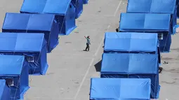 Seorang gadis Lebanon yang mengungsi bermain di antara tenda-tenda biru yang didirikan pemerintah untuk orang-orang yang meninggalkan rumah dan desa mereka di pinggiran selatan Beirut dan Lebanon Selatan, Jumat 22 Mei 2026. (Anwar AMRO/AFP)