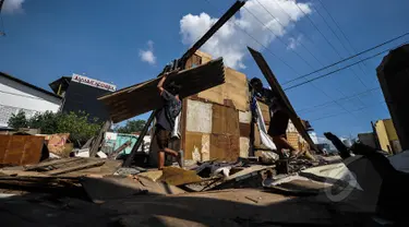 Warga mengambil sisa puing bangunan seusai penertiban bangunan liar di sepanjang bantaran tanggul barat Kali Angke, Jakarta, Senin (30/3/2015). Pembongkaran dilakukan lantaran lokasi tersebut diperuntukkan sebagai jalur hijau. (Liputan6.com/Faizal Fanani)