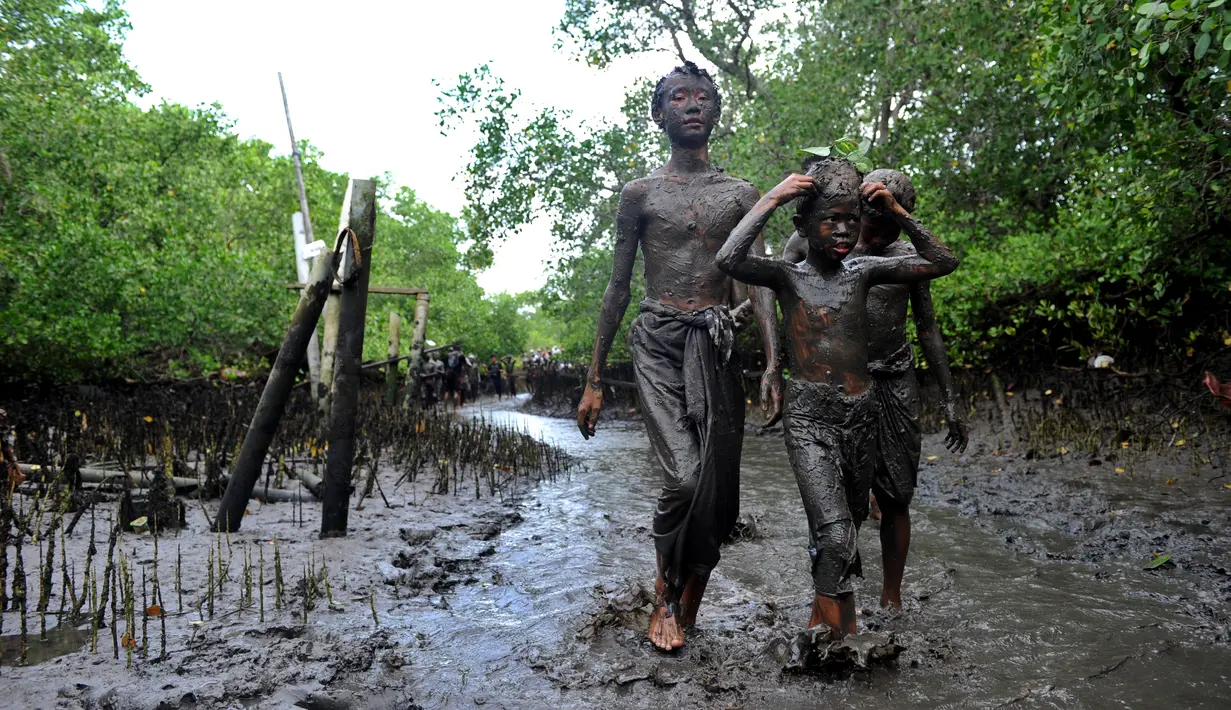 Sejumlah anak berjalan berlumur lumpur saat mengikuti tradisi Mebuug-buugan atau mandi lumpur di desa Kedonganan, Denpasar, Bali (10/3). Mebuug-buugan diadakan sehari usai hari raya Nyepi. (AFP/Sonny Tumbelaka)
