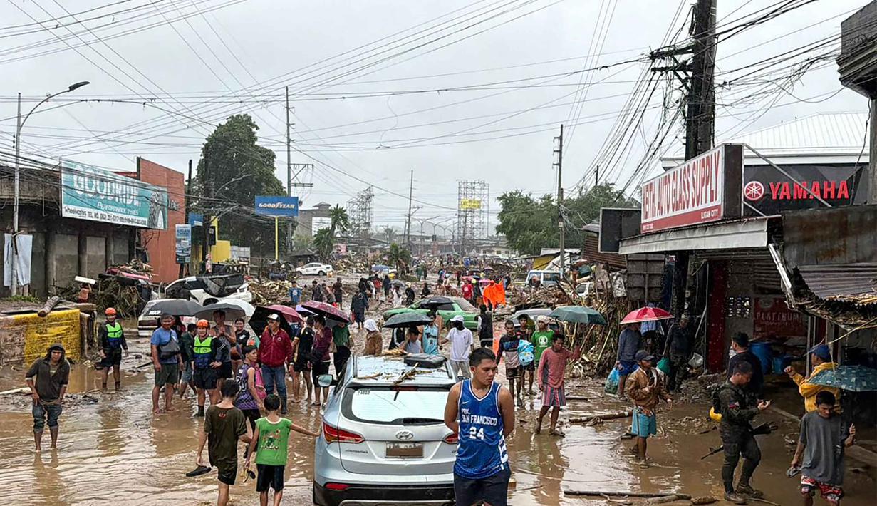 Diketahui, badai tropis Penha menghantam daratan di Provinsi Surigao del Sur di Tenggara dari Samudra Pasifik pada Kamis 5 Februari 2026 malam. Tampak dalam foto, warga berjalan menerobos genangan air yang dibawa oleh Badai Tropis Penha di Iligan, provinsi Lanao del Norte, Filipina, pada Jumat 6 Februari 2026. (Merlyn Manos/AFP)