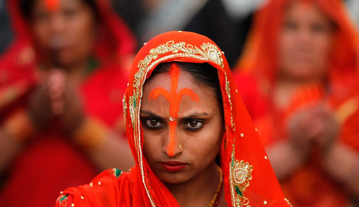 Ekspresi seorang wanita Nepal yang mengenakan bubuk vermilion saat melakukan doa di tepi Sungai Bagmati selama festival Chhath Puja di Kathmandu, Nepal (26/10). Acara ini merupakan ritual Hindu kuno. (AP Photo/Niranjan Shrestha)