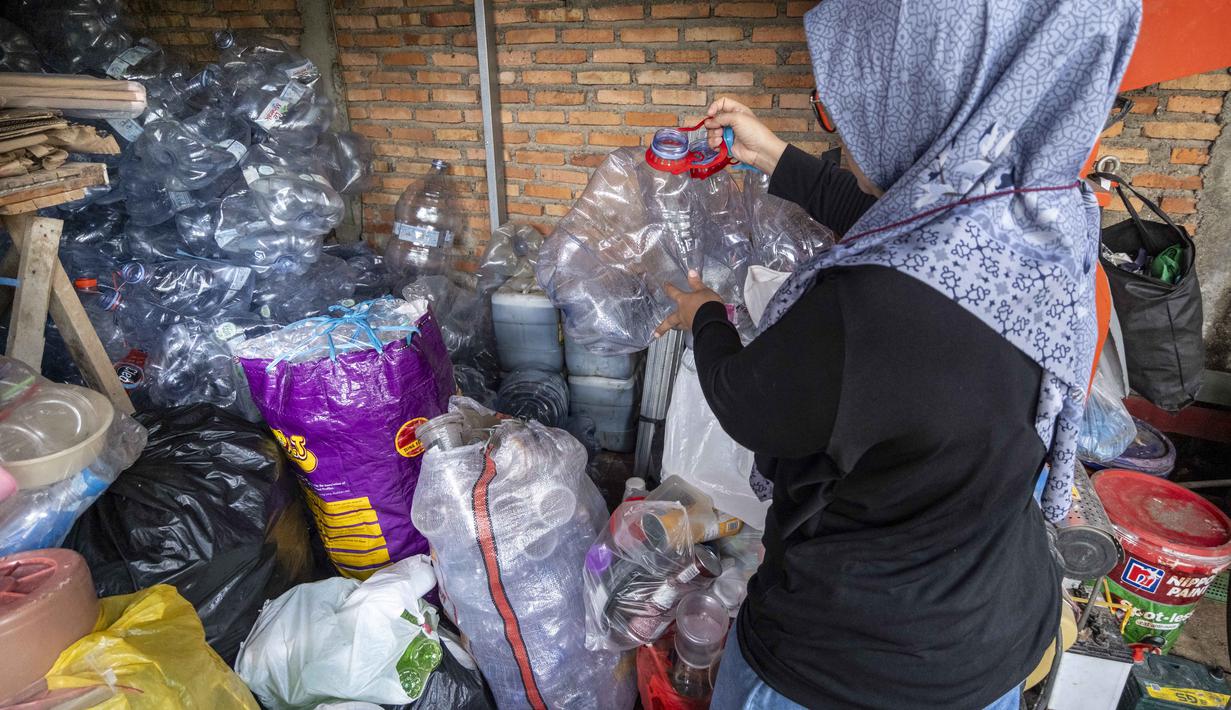 Seorang pegawai bank sampah memilah sampah anorganik rumah tangga, baik berupa karton maupun botol plastik, Jakarta, Kamis 4 Juni 2026, sebagai bagian dari instruksi Pemprov DKI yang mewajibkan warga memilih dan memilah sampah untuk mengurangi beban sampah yang semakin menumpuk di ibu kota. (BAY ISMOYO/AFP)
