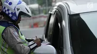 Polisi memberikan surat tilang kepada pengemudi mobil yang melanggar sistem ganjil genap di Jalan MT Haryono, Jakarta, Rabu (1/8). Hari pertama pemberlakuan sistem ganjil genap, pelanggar dikenakan sanksi Rp 500 ribu. (Merdeka.com/Iqbal S. Nugroho)