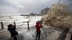Dua orang wanita mengambil gambar ombak yang menghantam hingga ke jalan saat serangan badai di Cape Town, Afrika Selatan, Rabu (7/6). Media setempat melaporkan beberapa orang tewas oleh kuatnya badai yang menghantam kawasan tersebut (AP Photo/Halden Krog)