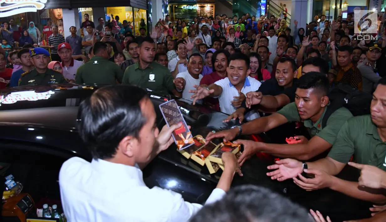 Presiden Jokowi membagikan kenang-kenangan kepada warga saat menyambangi Palembang Square, Palembang (21/1). Setelah berada selama hampir 45 menit, presiden meninggalkan mal tersebut.  (Liputan6.com/Pool/Biro Setpres)