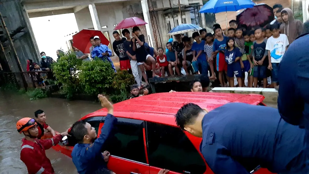 Sejumlah petugas Pemadam Kebakaran dibantu warga mengevakuasi mobil yang tercebur di Kali Pondok Depok