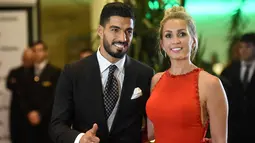 Pemain Barcelona, Luis Suarez dan istrinya Sofia Balbi berpose di karpet merah saat menghadiri pernikahan Lionel Messi di Rosario, Argentina (30/6). (AFP Photo/Eitan Abramovich)