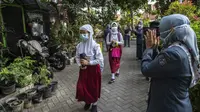Guru menyapa para siswa sebelum mengikuti pembelajaran tatap muka (PTM) di sebuah sekolah di Surabaya, Jawa Timur, Senin (6/9/2021). Pemerintah kembali membuka sekolah di tengah pandemi COVID-19. (JUNI KRISWANTO/AFP)