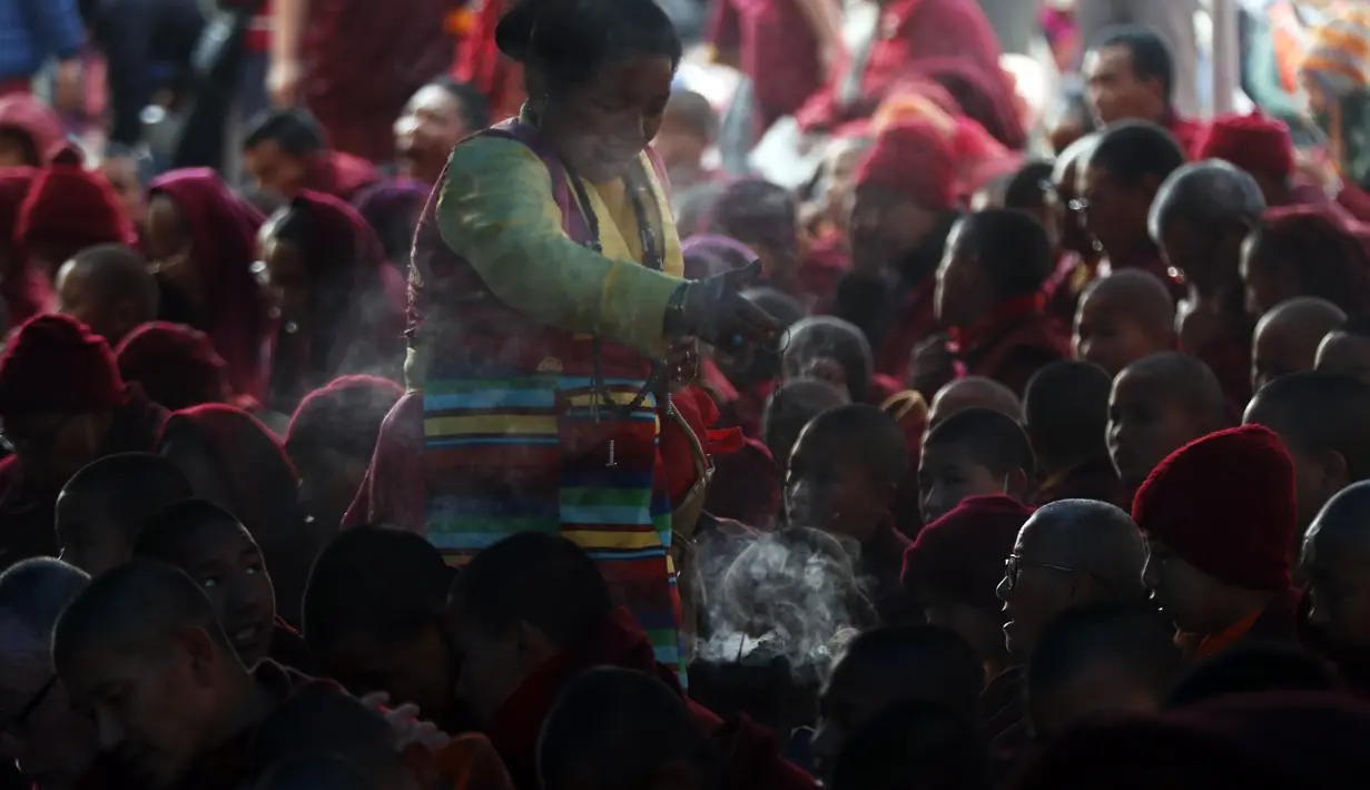 Seorang wanita Budha berkeliling menyalakan dupa ketika para biksu membaca kitab selama festvial Budha yang merupakan rangkain Monlam di Kathmandu, Nepal (7/1/2020). Monlam adalah acara tahunan di mana para biksu berdoa untuk perdamaian dunia. (AP Photo/Niranjan Shrestha)