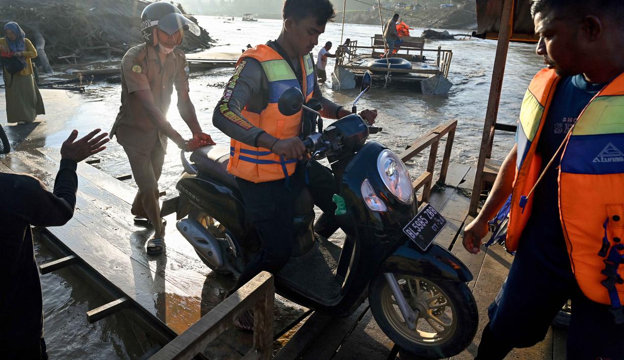 Sementara itu, Balai Pelaksanaan Jalan Nasional (BPJN) Aceh sudah memproyeksikan pembangunan kembali jembatan permanen di wilayah terdampak Sungai Peusangan dimulai pada tahun 2026. Tampak dalam foto, masyarakat menggunakan rakit tali untuk menyeberangi Sungai Peusangan menyusul banjir bandang yang menghancurkan desa-desa di sekitarnya di Kabupaten Bireuen, provinsi Aceh, pada Senin 5 Januari 2026. (CHAIDEER MAHYUDDIN/AFP)