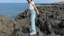 Saat pergi ke pantai, Hyeri tampil kasual dengan celana jeans dan kaus tipis berwarna putih. Ia melengkapi [enampilannya dengan sneakers dan bucket hat berwarna senada. [Foto: Instagram/hyeri_0609]