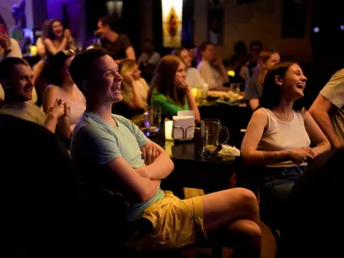 Orang-orang menghadiri pertunjukan stand-up comedy Serhiy Lipko di Kyiv, Ukraina, 11 Juni 2022. Perang Ukraina tidak terlalu lucu, tetapi orang-orang di sana belajar menertawakan kengerian itu semua untuk tetap waras dalam konflik yang telah menewaskan puluhan ribu orang tersebut. (AP Photo/Natacha Pisarenko)