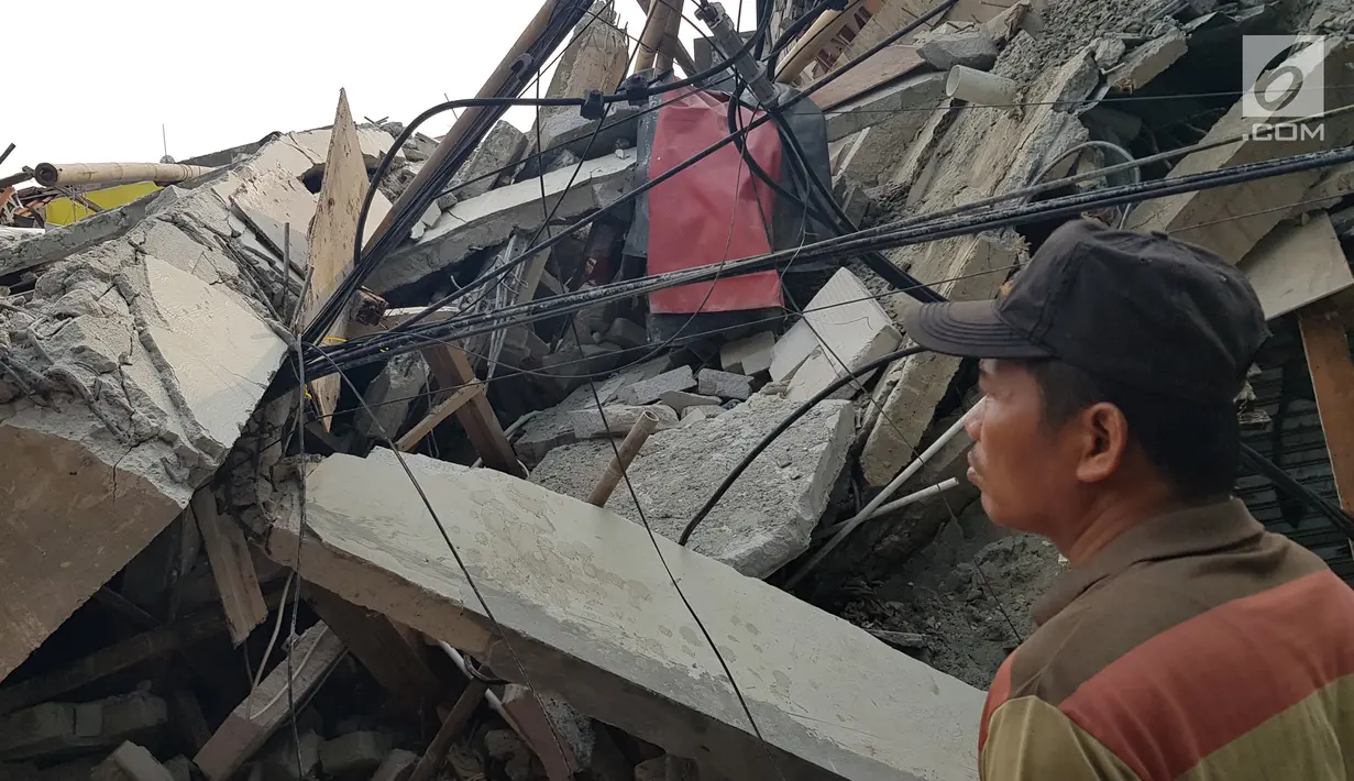 Warga melihat rumah roboh di  Jalan Pulo, Tanah Tinggi, Johar Baru, Jakarta Pusa, Jumat (26/4). Hingga saat ini petugas masih melakukan evakuasi warga yang masih terjebak di dalam puing bangunan rumah yang ambruk. (Liputan6.com/Herman Zakharia)