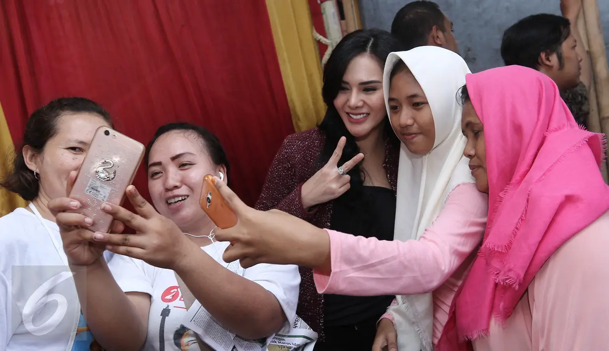 Warga berfoto bersama aktris Puy Brahmantya saat blusukan ke ke Cilincing, Jakarta, Selasa (11/4). Hasto mengajak Puy blusukan untuk serap aspirasi program KJP, KJS dan tata ruang kota Jakarta. (Liputan6.com/Herman Zakharia)