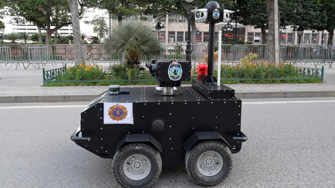 Robot polisi Tunisia berpatroli selama kebijakan penguncian (lockdown) di sepanjang Avenue Habib Bourguiba, pusat ibu kota Tunis, Rabu (1/4/2020). Robot itu dikendalikan dari jarak jauh untuk berkeliling dan membagikan sanksi terhadap warga yang melanggar aturan karantina. (FETHI BELAID/AFP)
