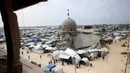 Kondisi bangunan yang nyaris rata dengan tanah dan miring, tidak menyurutkan niat mereka untuk tetap beribadah di lokasi tersebut. Tampak dalam foto, umat Muslim Palestina berdoa saat salat Jumat terakhir di bulan suci Ramadan 1447 Hijriah, di luar Masjid Al-Talbani, yang dihancurkan oleh militer Israel di Khan Yunis, Jalur Gaza selatan pada Jumat 13 Maret 2026. (Bashar Taleb/AFP)