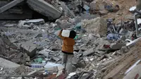 Saat ini jutaan anak masih menghadapi masalah-masalah yang sering membuat mereka merasa terancam hingga menimbulkan rasa takut. Tampak dalam foto, seorang anak laki-laki Palestina membawa sebuah wadah plastik saat dia berjalan melewati puing-puing di samping sebuah bangunan yang hancur akibat pemboman Israel baru-baru ini di Khan Yunis di Jalur Gaza selatan pada 19 November 2024. (Eyad BABA/AFP)