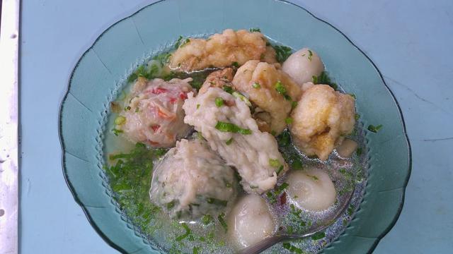 Beberapa baso, pangsit dan baso aci tercampur dengan lengkap dalam satu mangkuk baso cuanki