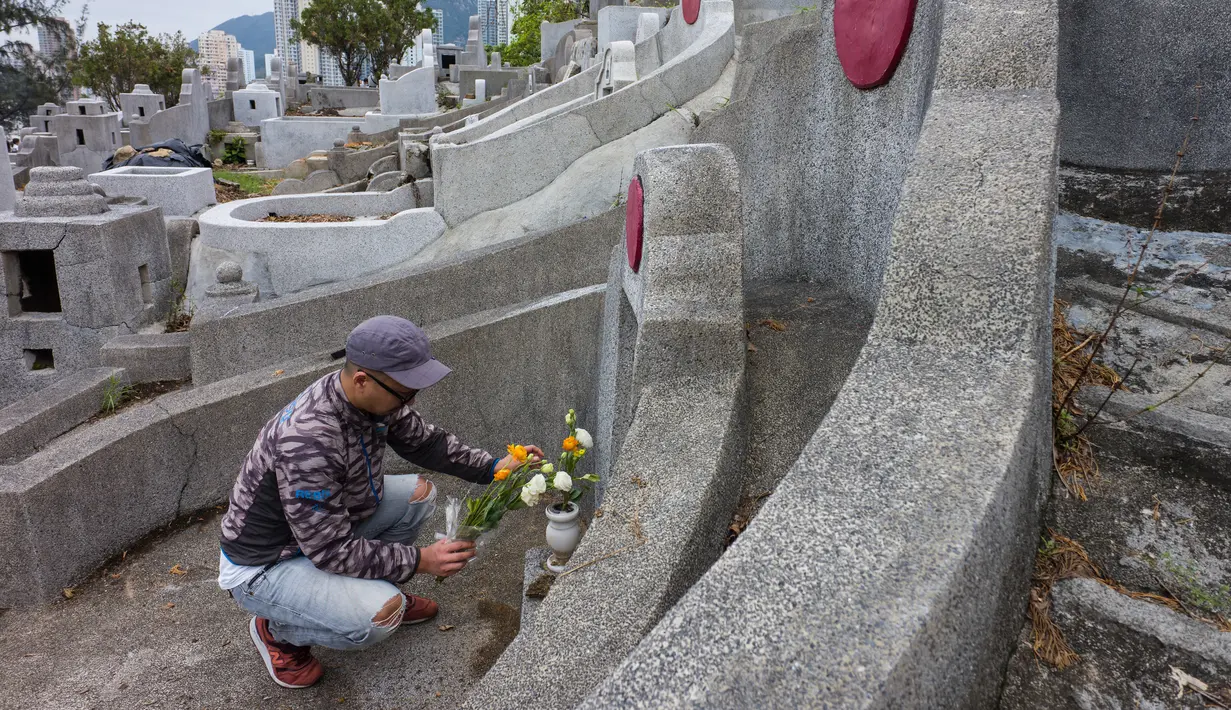 Seorang pria meninggalkan persembahan di makam kerabat saat Festival Chung Yeung atau Tomb Sweeping Day di Hong Kong, 17 Oktober 2018. Pada saat festival, ribuan warga memberi penghormatan kepada leluhur mereka yang meninggal.  (Anthony WALLACE/AFP)
