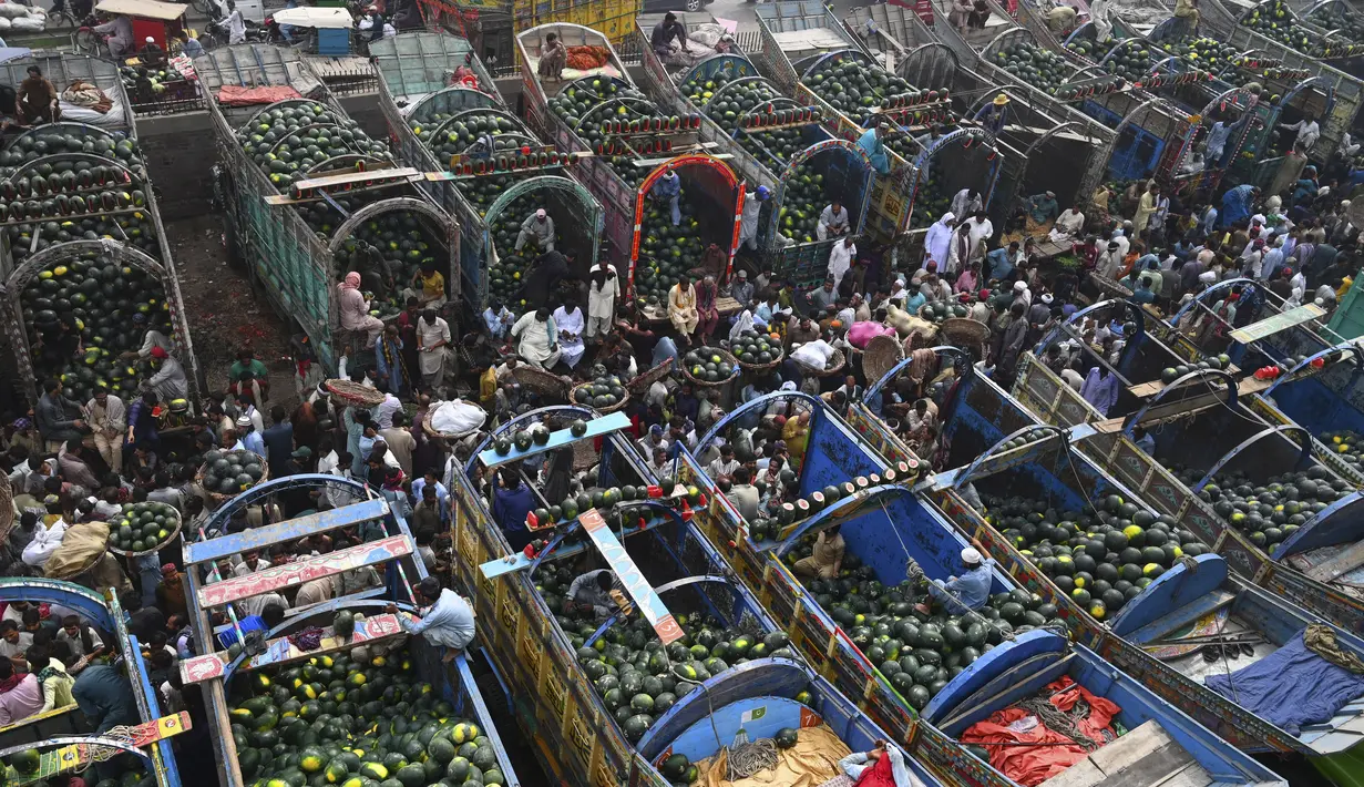 Orang-orang berdagang semangka di pasar buah di Lahore, Pakistan (12/4/2022).  Semangka biasa dipanen buahnya untuk dimakan segar atau dibuat jus. (AFP/Arif Ali)