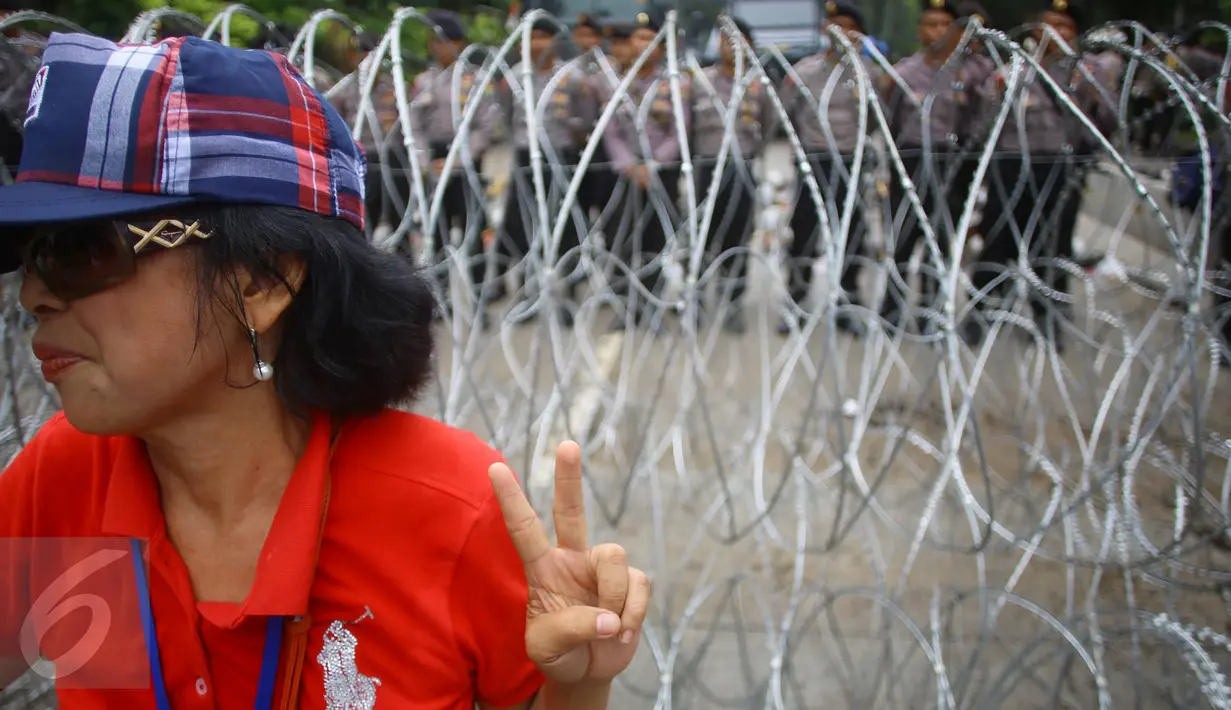 Pendukung Cagub DKI Basuki T Purnama memberikan salam dua jari saat sidang kasus penistaan agama, Jakarta, Selasa (10/1). Dengan mengenakan atribut kotak-kotak, massa membawa bendera Indonesia serta melakukan orasi damai. (Liputan6.com/Immanuel Antonius)