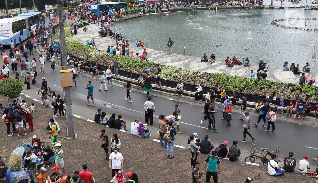 Warga duduk-duduk untuk beristirahat di Jalan Jendral Sudirman dan MH Thamrin ketika pelaksanaan car free day (CFD) di Jakarta, Minggu (11/2). Warga berolahraga atau sekadar berjalan-jalan di hari bebas kendaraan tersebut. (Liputan6.com/Immanuel Antonius)