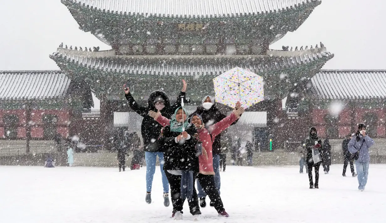 Pengunjung berswafoto di tengah salju di Istana Gyeongbok, istana kerajaan utama selama Dinasti Joseon dan salah satu landmark terkenal Korea Selatan di Seoul, Korea Selatan, 15 Desember 2022. (AP Photo/Ahn Young-joon)