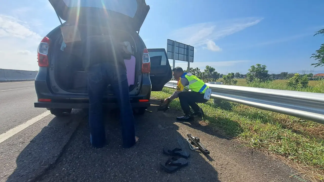 Polisi bantu mengganti ban mobil pemudik yang pecah di Tol Pemalang-Batang. (Foto: Liputan6.com/Polres Pemalang)