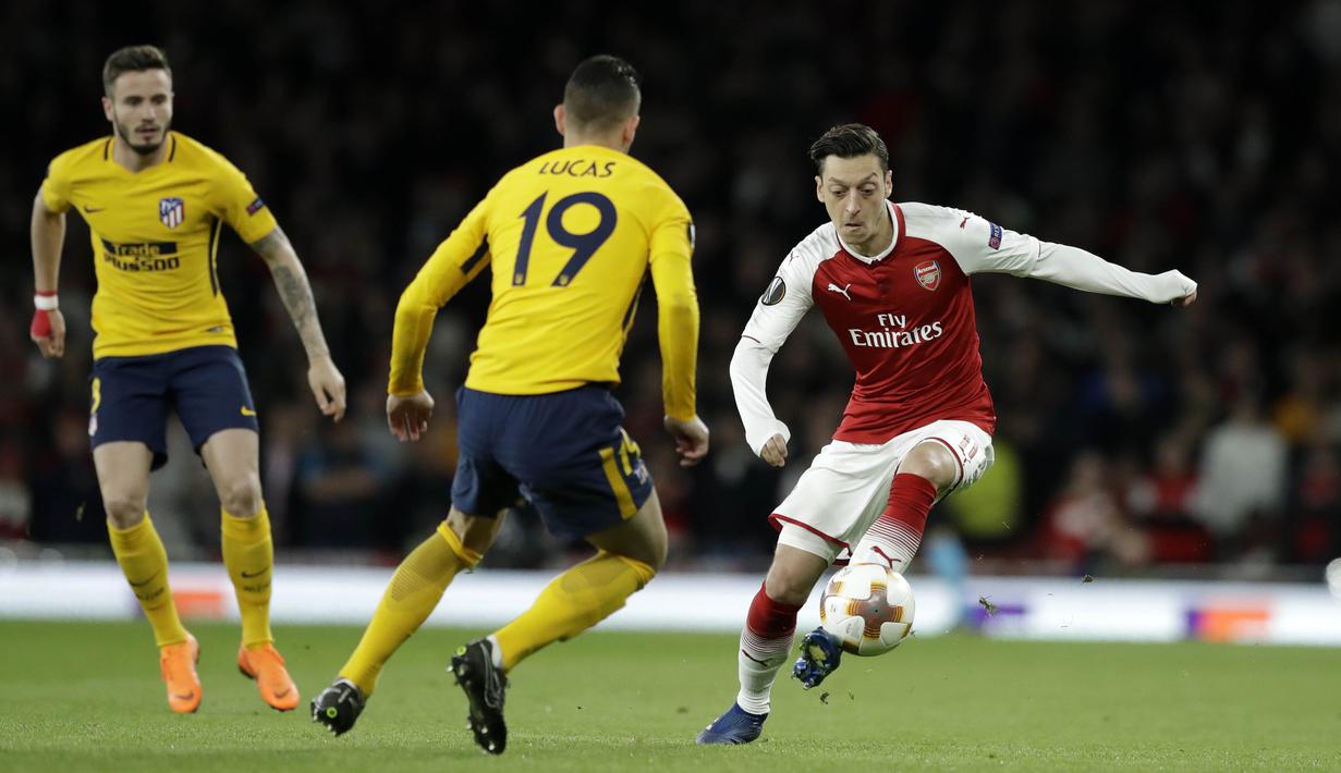 Gelandang Arsenal, Mesut Ozil, berusaha melewati bek Atletico Madrid, Lucas Hernandez, pada laga semifinal Liga Europa di Stadion Emirates, Kamis (26/4/2018). Arsenal ditahan 1-1 oleh Atletico Madrid. (AP/Matt Dunham)