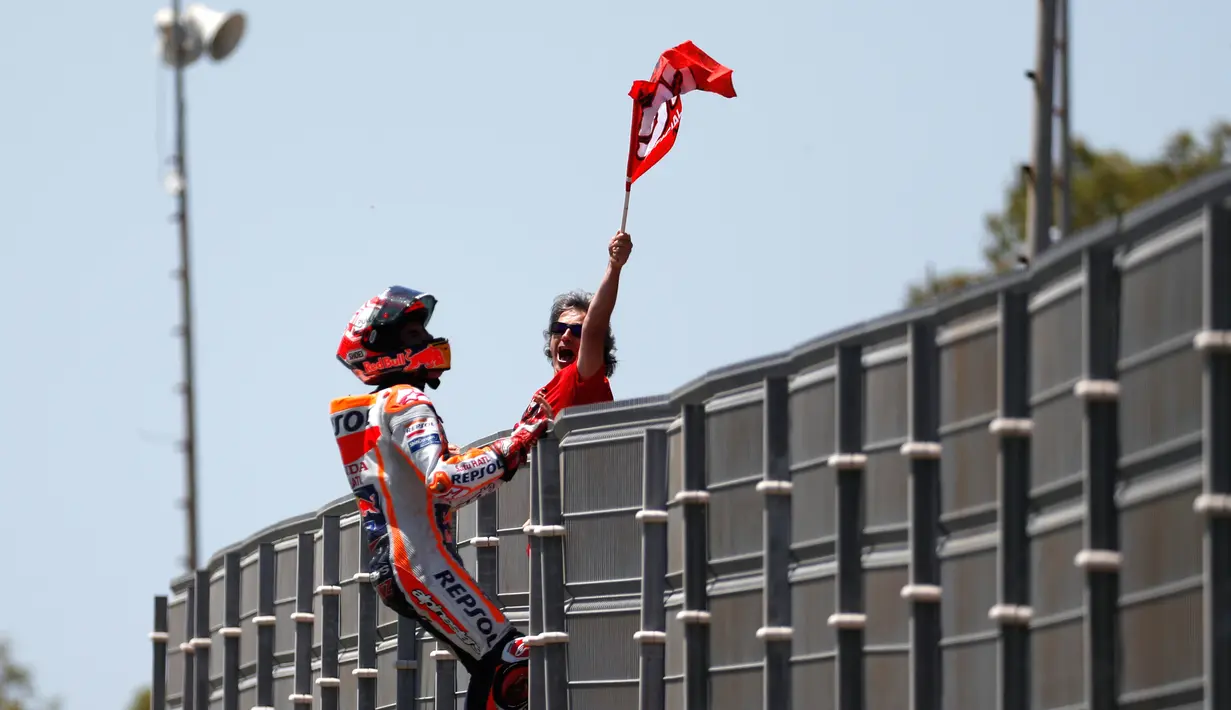 Pembalap Repsol Honda, Marc Marquez memanjat pagar lintasan setelah berhasil finis pertama pada balapan MotoGP Spanyol 2018 di Sirkuit Jerez, Minggu (6/5). Marquez mengukir waktu 41 menit 39,678 detik. (AP Photo/Miguel Morenatti)