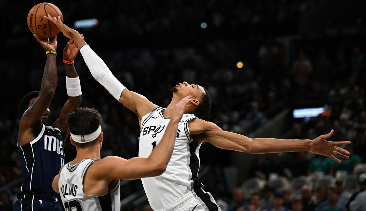 Pebasket San Antonio Spurs, Victor Wembanyama (kanan) berusaha merebut bola dari pebasket Dallas Mavericks pada laga pertama NBA musim 2023/2024 di AT&T Center in San Antonio, Texas, Kamis (27/10/2023). Ini merupakan laga perdana bagi Wembanyama di NBA. (AFP/Chandan Khanna)
