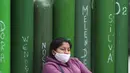 Seorang wanita beristirahat di samping tangki oksigen yang kosong di luar toko isi ulang, Callao, Peru, Senin (25/1/2021). Di tengah pandemi COVID-19, beberapa orang mengatakan mereka telah antre sehari sebelumnya untuk menjadi yang pertama saat toko buka. (AP Photo/Martin Mejia)