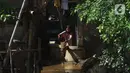 Seorang anak membersihkan rumah dari sisa lumpur di Bukit Duri, Jakarta, Jumat (29/10/2021). Hujan dengan intensitas tinggi beberapa hari lalu membuat aliran sungai ciliwung meluap yang merendam sebagian rumah warga yang tinggal di bantaransungai  tersebut. (merdeka.com/Imam Buhori)