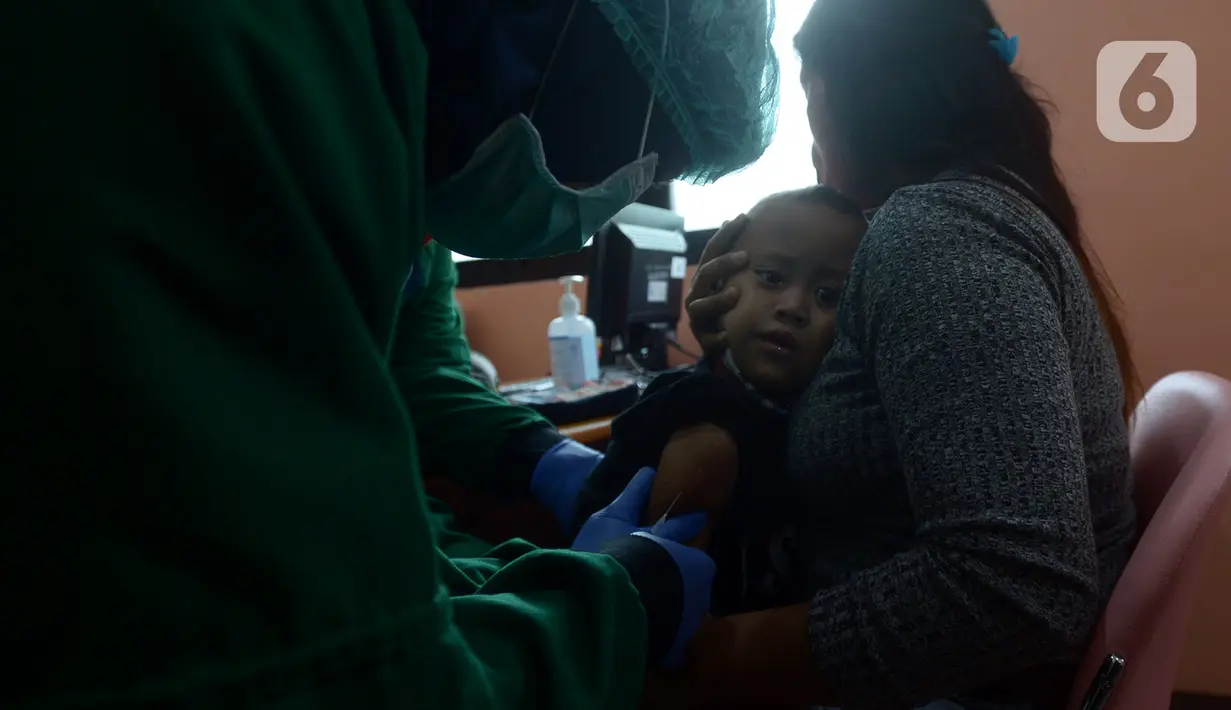 Dokter menyuntikkan imunisasi campak lanjutan pada anak di Puskesmas Kramat Jati, Jakarta, Kamis (12/11/2020). Pemantauan pertumbuhan balita dan batita dengan mengikuti imunisasi secara rutin pada anak usia 0-9 bulan dan 18 bulan untuk imunisasi tambahan mencegah penyakit. (merdeka.com/Imam Buhori)