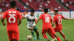 Pemain Indonesia Asnawi Mangkualam Bahar (kedua kiri) menggiring bola melewati para pemain Singapura pada pertandingan leg pertama semifinal Piala AFF 2020 di National Stadium, Singapura, Rabu (22/12/2021). Pertandingan berakhir imbang 1-1. (Roslan RAHMAN/AFP)