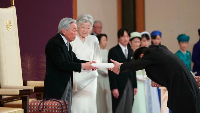 Kaisar Akihito menyerahkan teks pidato kepada bendahara agung usai menyampaikan berpidato dalam upacara turun takhta di Istana Kekaisaran, Tokyo, Jepang, Jumat (30/4/2019). Kaisar Akihito resmi turun takhta setelah tiga dekade memimpin. (Japan Pool via AP)