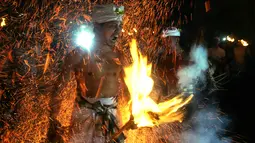 Ekspresi seorang pria Bali saat dipukul dengan daun kelapa yang menyala dalam ritual Lukat Gni di Klungkung, Bali (16/3). (AP Photo / Firdia Lisnawati)