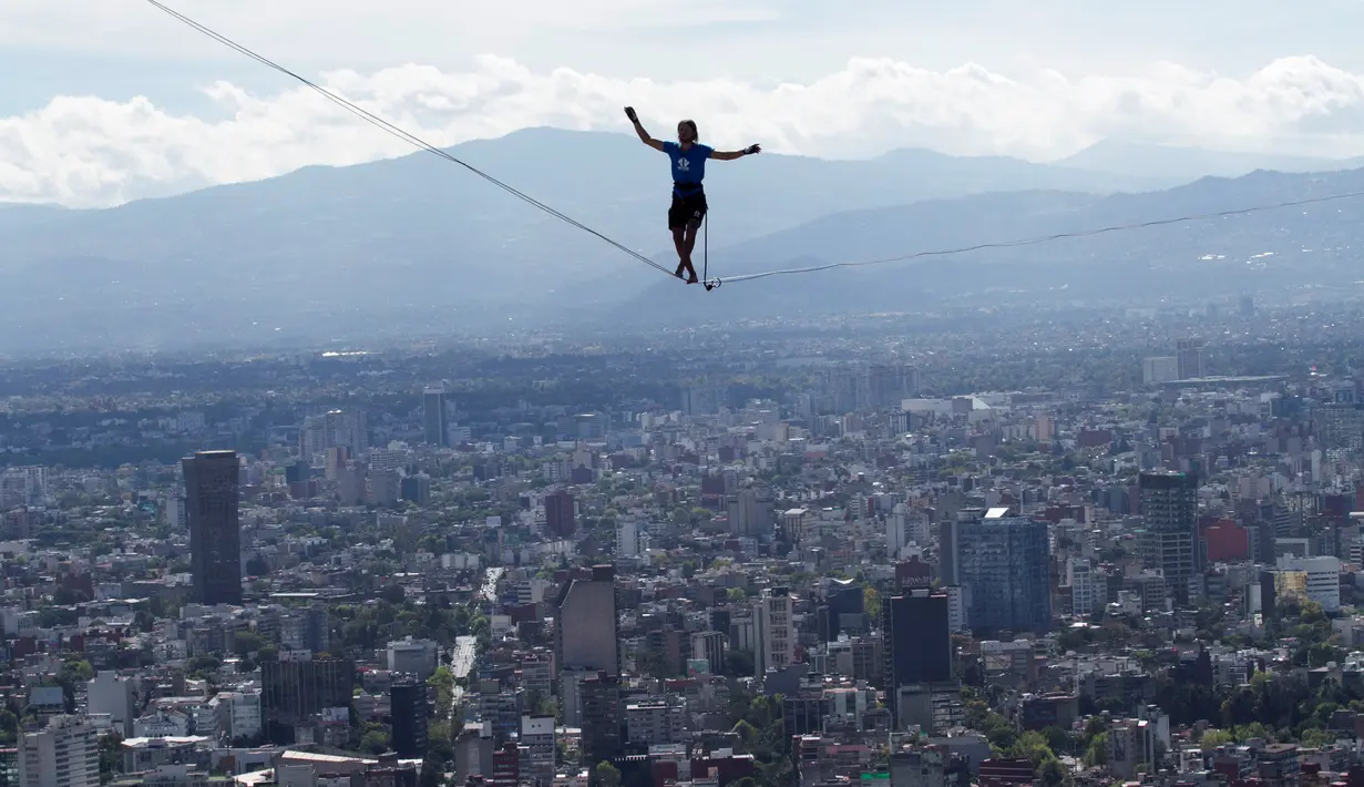 Aksi nekat Alexander Schultz berjalan di antara dua gedung tertinggi Mexico City menggunakan tali pada ketinggian 246 meter di Meksiko, 4 Desember 2016. Schultz butuh lima kali usaha menaklukkan tali sepanjang 217 meter itu. (REUTERS/Stringer)