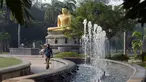 Seorang pria berjalan di depan patung Buddha di Taman Viharamahadevi di Kolombo, Sri Lanka (3/1). Taman tertua dan terbesar dari Pelabuhan Kolombo, terletak di depan gedung Balai Kota bergaya kolonial. (AFP Photo/Lakruwan Wanniarachchi)
