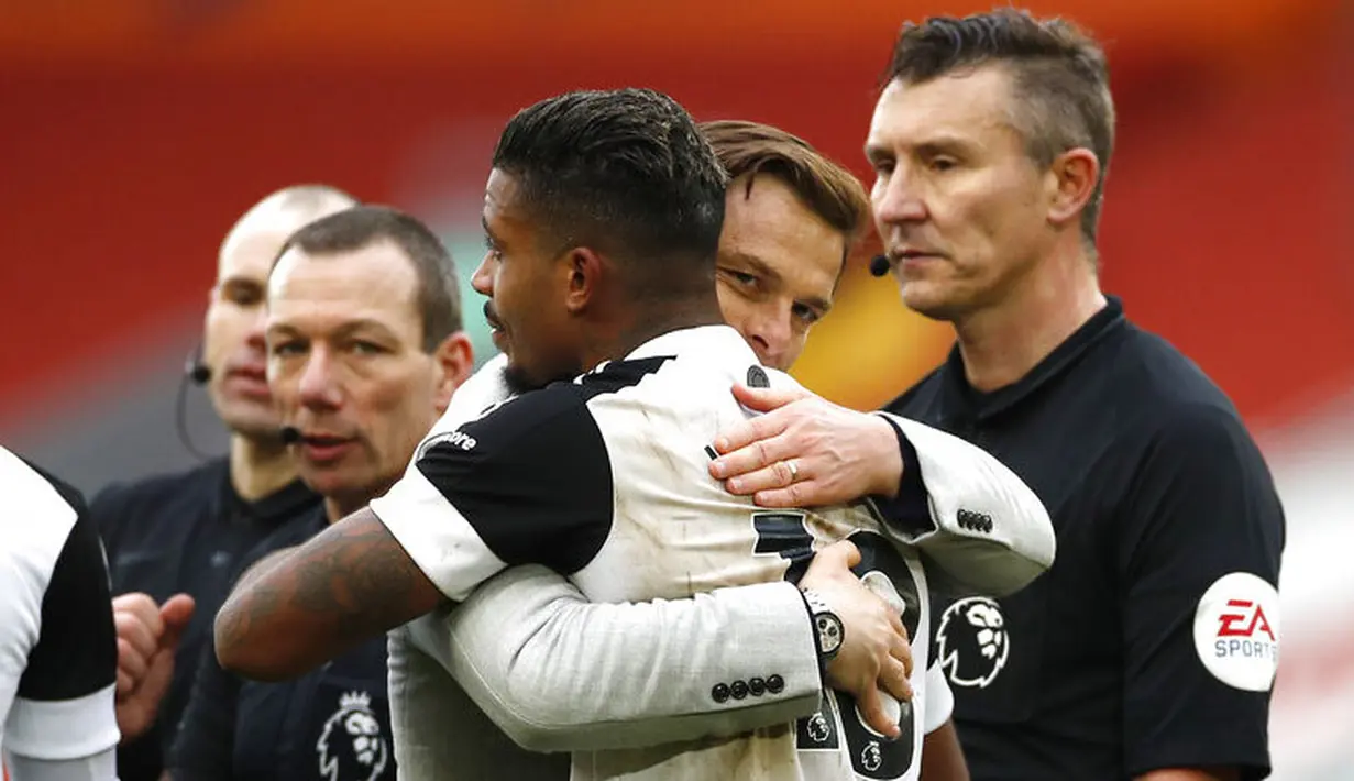 Pelatih Fulham, Scott Parker, memeluk Mario Lemina usai berhasil menaklukkan Liverpool pada laga Liga Inggris di Stadion Anfield, Minggu (7/3/2021). Fulham menang dengan skor 0-1. (Phil Noble/Pool via AP)