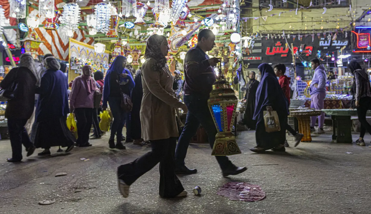 Seorang pria membawa lentera tradisional yang dibelinya jelang bulan suci Ramadhan di Distrik Sayyida Zeinab, Kairo, Mesir, 30 Maret 2022. Umat muslim Mesir memperketat dompet mereka jelang Ramadhan saat pengeluaran meningkat karena mata uang lokal kehilangan 17 persen nilainya. (Khaled DESOUKI/AFP)