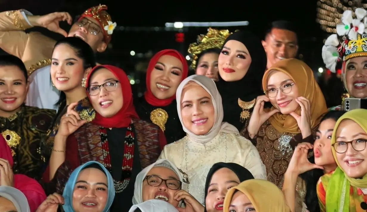 Bukan tas branded, kali ini ibu tiga anak itu melengkapi penampilannya dengan tas etnik rotan yang unik.