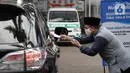 Petugas Amil Zakat melayani warga yang membayar zakat fitrah melalui sistem "drive thru" di Masjid Nurul Hidayah, Tanah Kusir, Jakarta, Selasa (19/5/2020). Layanan zakat "drive thru" selama pandemi COVID-19 ini diberlakukan dengan protokol kesehatan dan keselamatan. (Liputan6.com/ Johan Tallo)