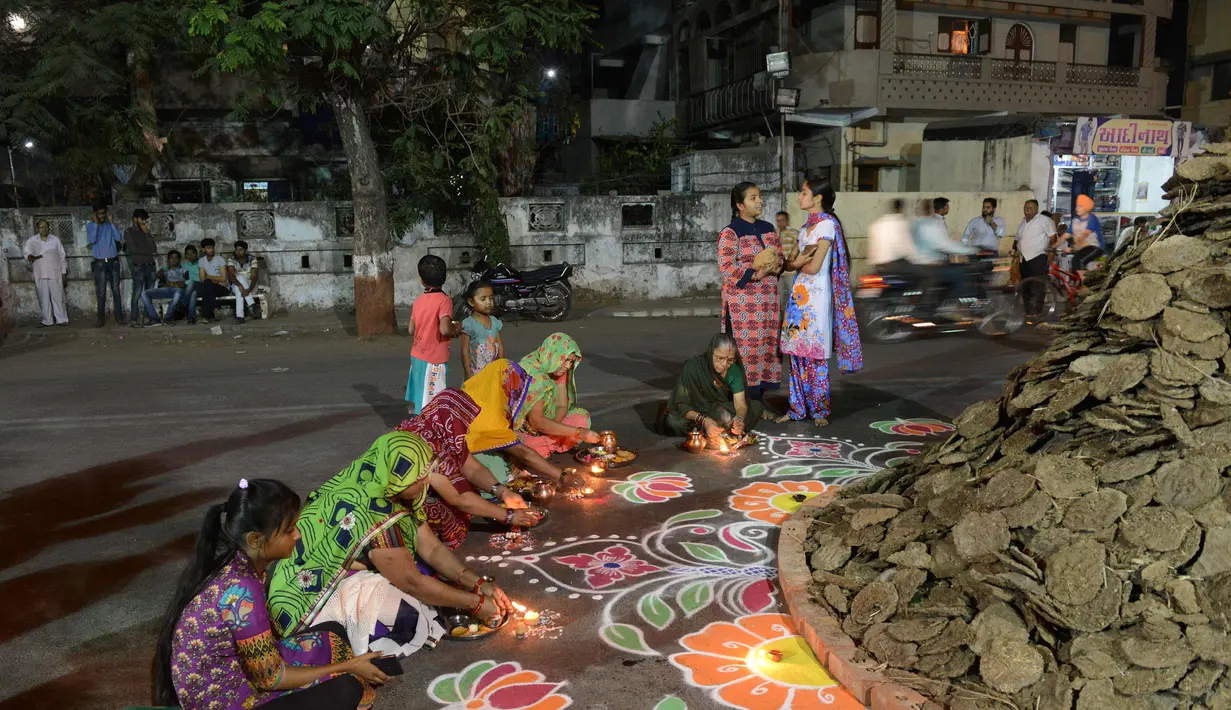 Warga bersiap di dekat Holika untuk melakukan ritual, Ahmedabad, India, Minggu (12/3). Bagi warga setempat Holika melambangkan kemenangan kebaikan atas kejahatan. (AFP PHOTO / SAM PANTHAKY)