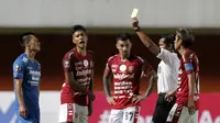 Pemain Bali United, I Made Andhika Pradana Wijaya, menerima kartu kuning dari wasit setelah melanggar pemain Persib Bandung dalam pertandingan Babak Penyisihan Piala Menpora 2021 di Stadion Maguwoharjo, Sleman. Rabu (24/3/2021). (Bola.com/Arief Bagus)