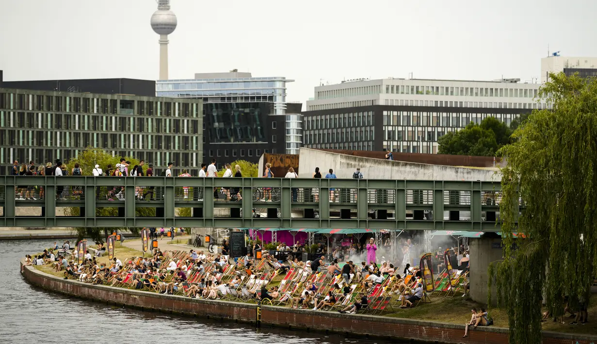 Orang-orang menikmati hari musim panas di sebuah bar di sungai Spree di pusat Berlin, Jerman, Minggu (19/6/2022). Orang-orang berbondong-bondong ke taman dan kolam renang di seluruh Eropa Barat untuk sedikit mendinginkan tubuh mereka dari gelombang panas awal. (AP Photo/Markus Schreiber)